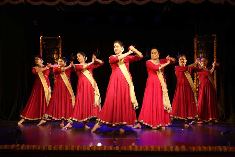 Kathak dancers in red costumes performing on stage