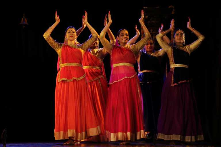 Kathak dancers with raised arms during a performance